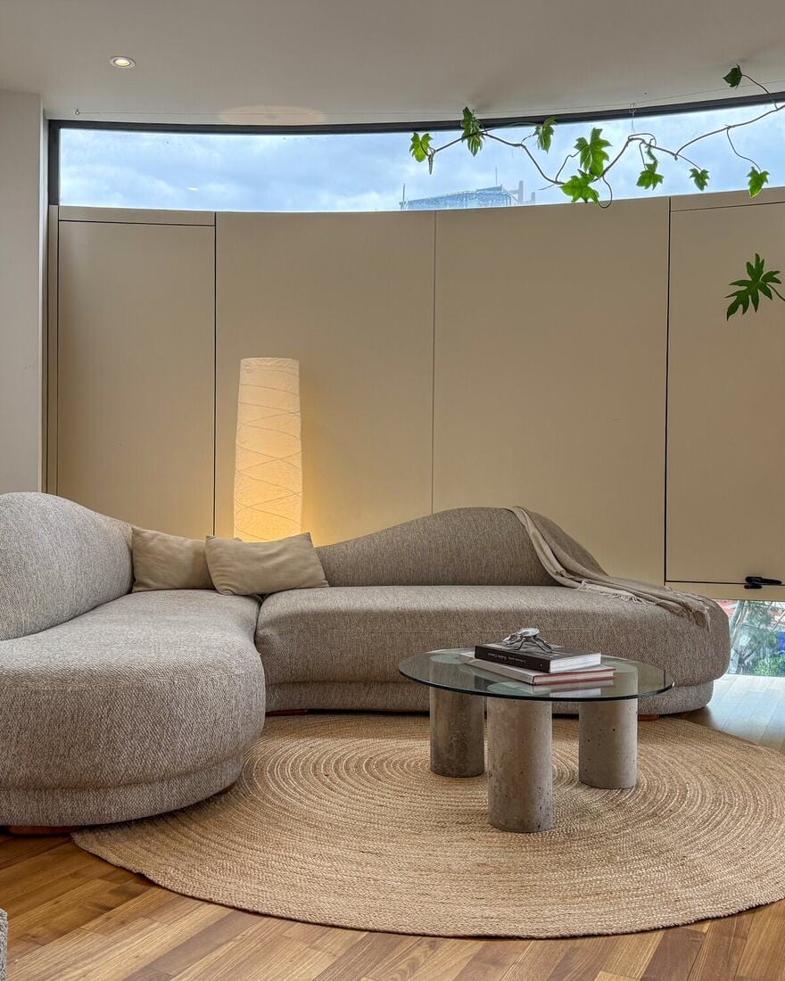 A penthouse living and dining area opening to a planted balcony with city and treetop views.